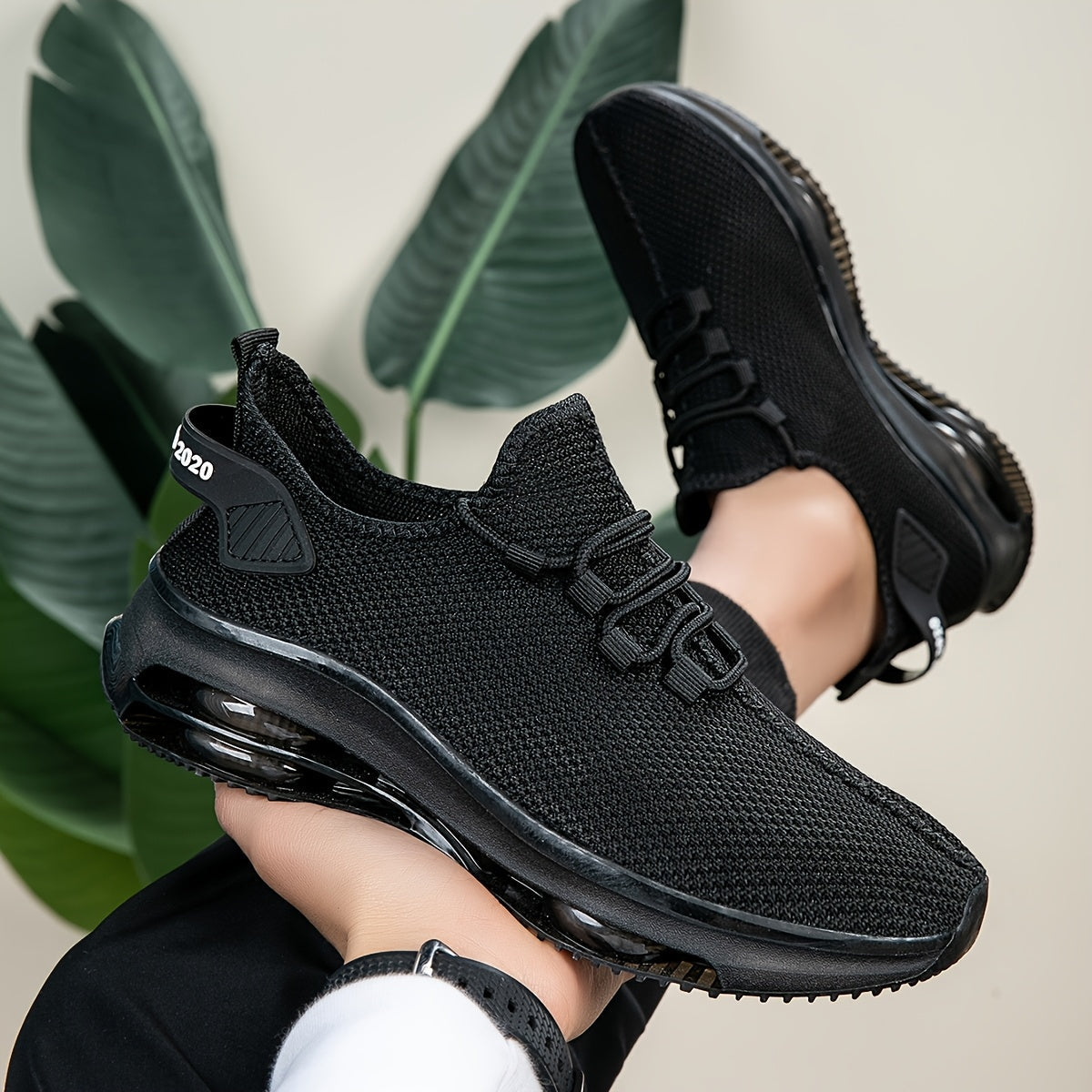 Black knit trainers with translucent sole, one shoe held up and one worn on foot