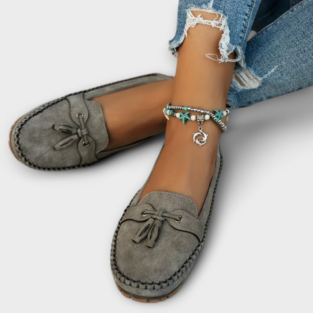 Close-up of tassel detail on women's suede moccasin flat loafers