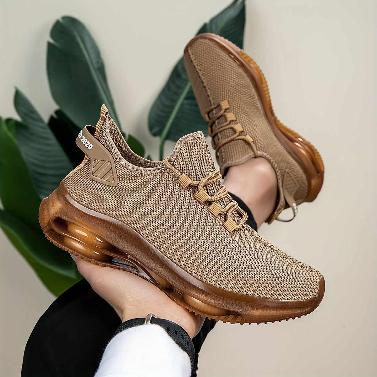 Khaki knit trainers with translucent amber sole, close-up hand-held view