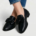 Black textured bow-detail loafers worn with cropped jeans, angled top view