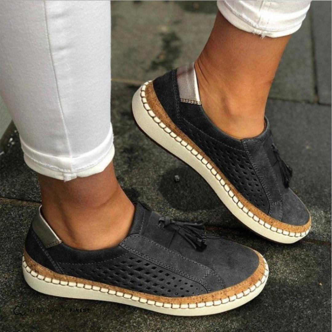 Women's perforated slip-on flat shoes in black – tassel detail side view