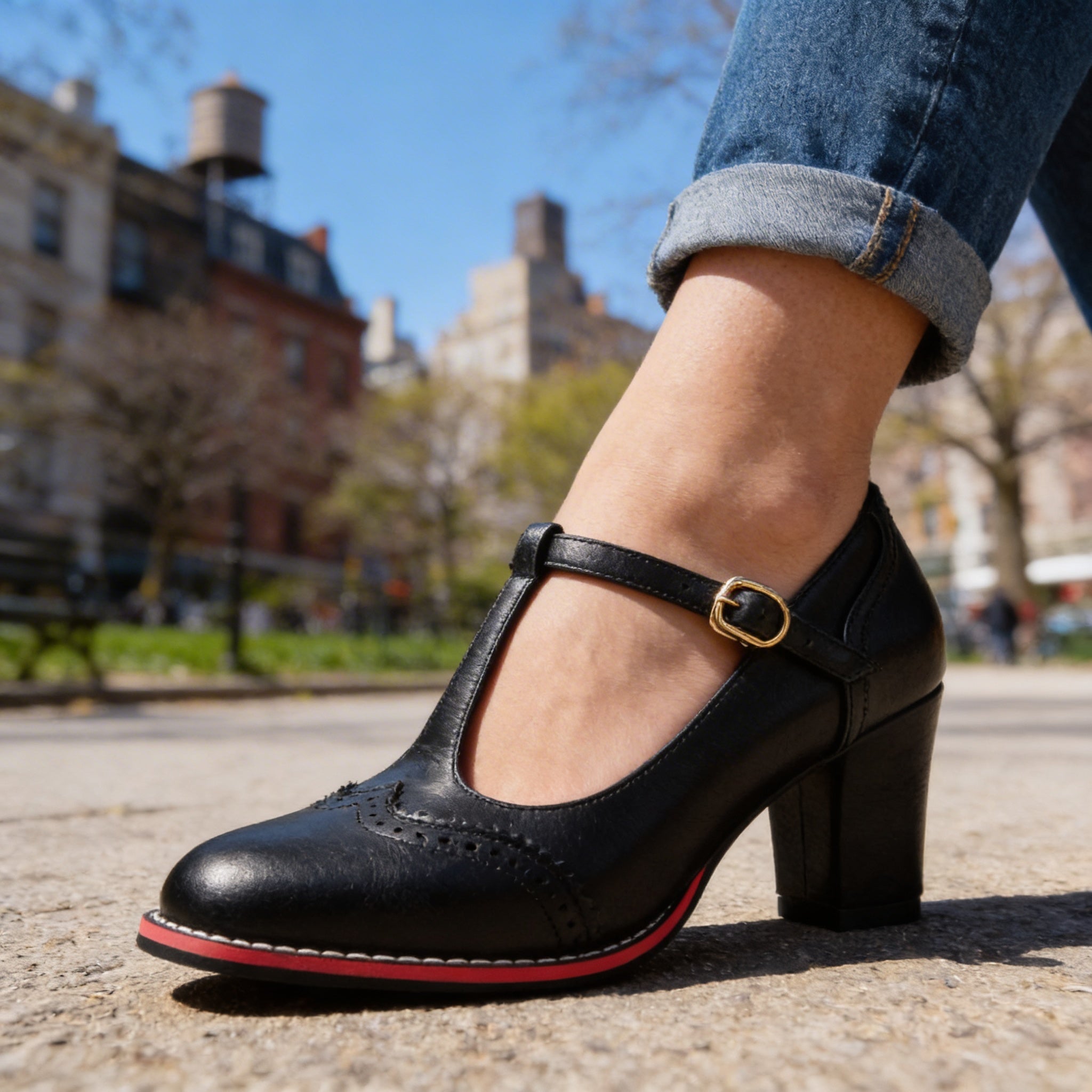 Close-up side view of black brogue Mary Jane block heel shoe with gold buckle
