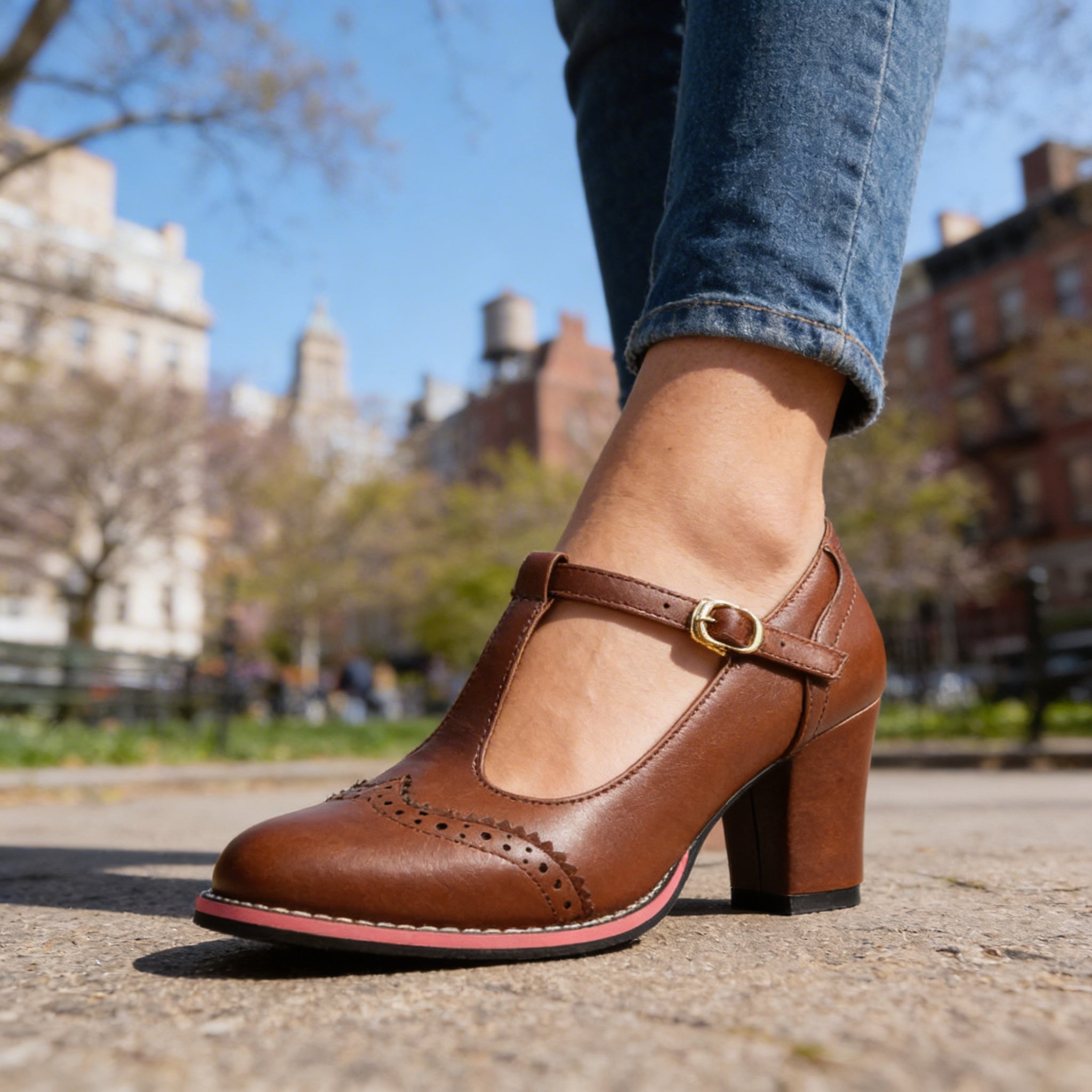 Close-up side view of brown brogue Mary Jane block heel shoe with gold buckle